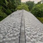 Newly installed gray architectural asphalt shingle roof with ridge cap