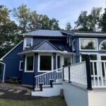 Blue two-story home with white wraparound deck railing, exterior project by Alt & Alt