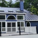 Blue home with a standing seam metal roof and white deck railing