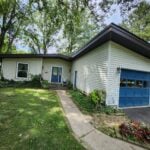 White-sided ranch home with a blue garage door after an exterior renovation
