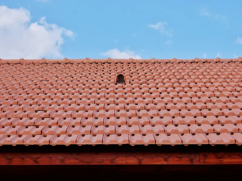 Close-up of red terracotta roof tiles with a vent.