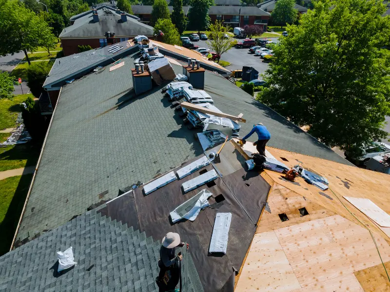 Aerial view of a large flat roof replacement with workers and materials.