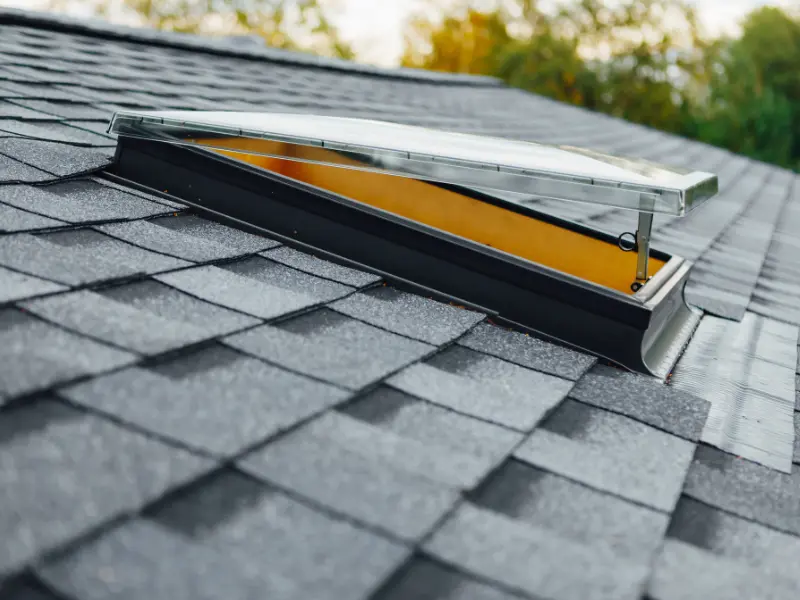 Open skylight window on a gray shingle roof.