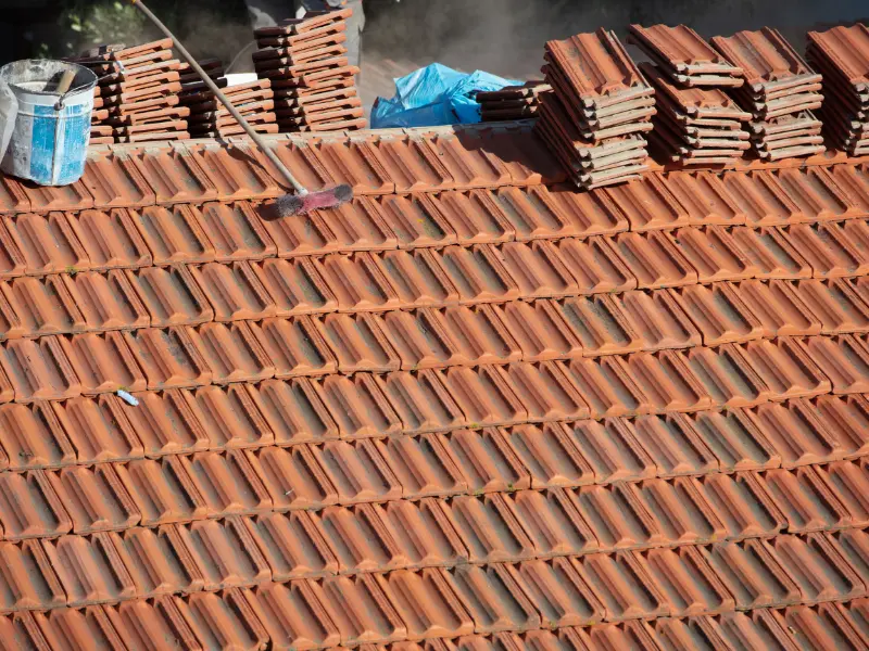 Stacks of terracotta roof tiles being laid on a roof.