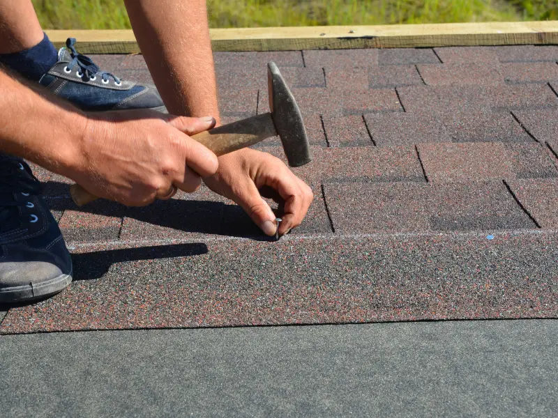Close-up of hands nailing asphalt shingles