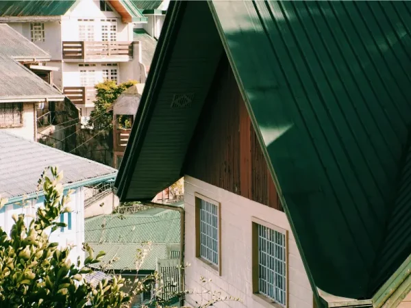 Green A-frame metal roof over a hillside home.