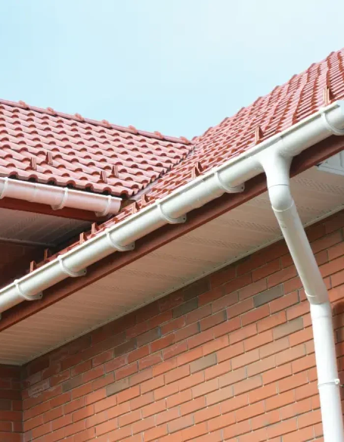 Red tile roof with gutter system on a brick house.